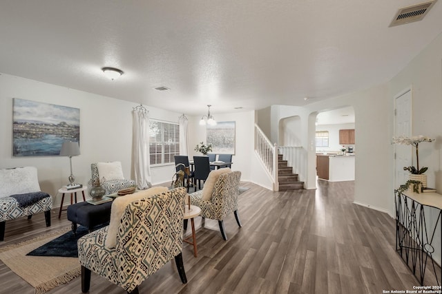 living room with a wealth of natural light, dark hardwood / wood-style flooring, a chandelier, and a textured ceiling