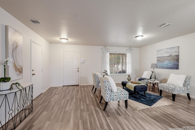 living room with light hardwood / wood-style floors and a textured ceiling