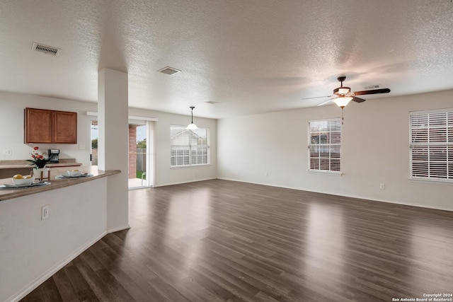 unfurnished living room featuring a healthy amount of sunlight, dark wood-type flooring, and a textured ceiling