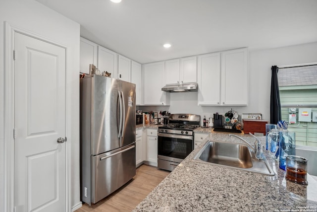 kitchen with light stone countertops, sink, appliances with stainless steel finishes, white cabinets, and light wood-type flooring