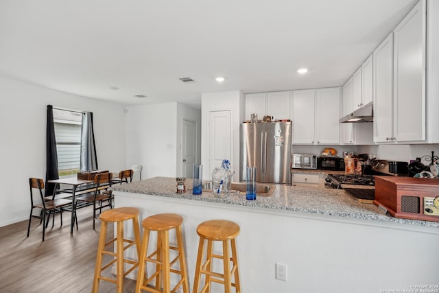 kitchen with light stone countertops, kitchen peninsula, light wood-type flooring, black appliances, and white cabinetry