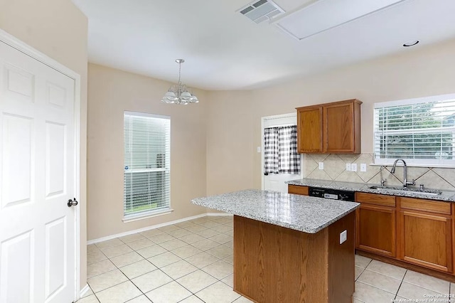 kitchen with sink, tasteful backsplash, light stone counters, decorative light fixtures, and a kitchen island