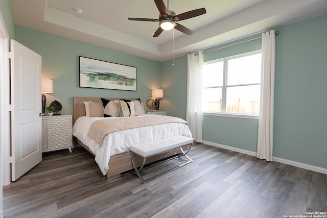 bedroom with a raised ceiling, ceiling fan, and hardwood / wood-style flooring