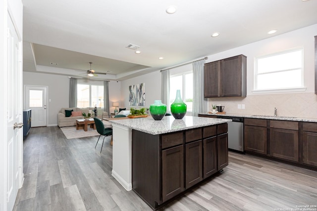 kitchen with light wood-type flooring, a tray ceiling, dark brown cabinetry, and sink