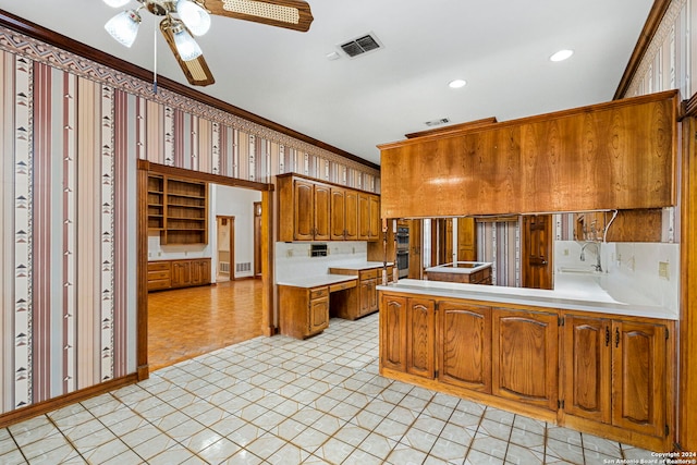 kitchen featuring kitchen peninsula, ceiling fan, stainless steel double oven, and ornamental molding