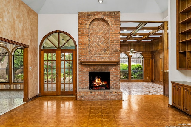 unfurnished living room with french doors, coffered ceiling, beamed ceiling, a fireplace, and light tile patterned floors