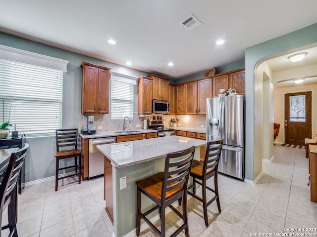 kitchen featuring a kitchen bar, decorative backsplash, a center island, and stainless steel appliances