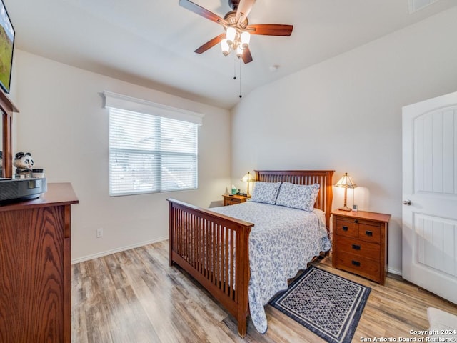 bedroom with ceiling fan, vaulted ceiling, and light hardwood / wood-style flooring