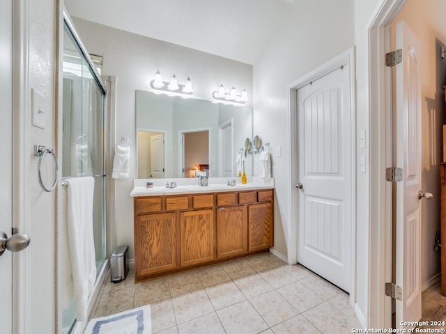 bathroom with a shower with door, vanity, lofted ceiling, and tile patterned flooring