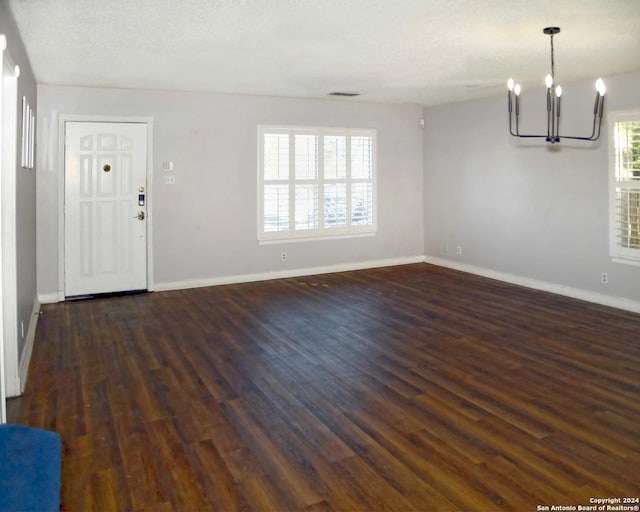 interior space featuring a textured ceiling, dark wood-type flooring, and a chandelier