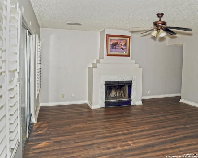 unfurnished living room with ceiling fan, dark hardwood / wood-style flooring, a high end fireplace, and a textured ceiling