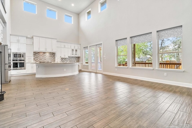 unfurnished living room featuring light hardwood / wood-style flooring and a high ceiling