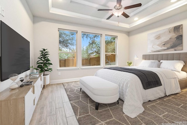 bedroom with hardwood / wood-style floors, ceiling fan, a raised ceiling, and crown molding