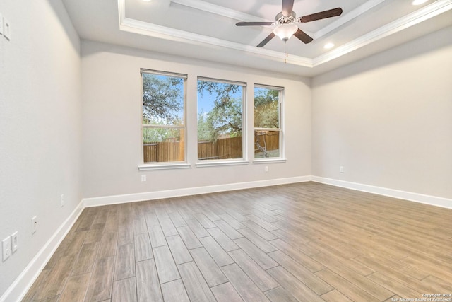 unfurnished room with light hardwood / wood-style floors, a raised ceiling, and crown molding