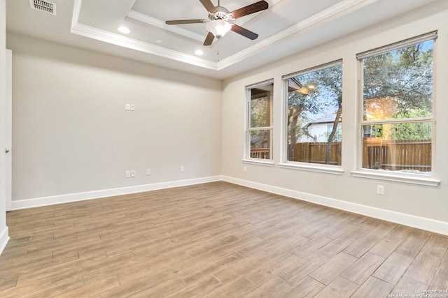 spare room featuring light hardwood / wood-style floors, a raised ceiling, plenty of natural light, and ornamental molding