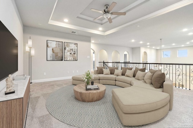 carpeted living room featuring a tray ceiling, ceiling fan, and crown molding