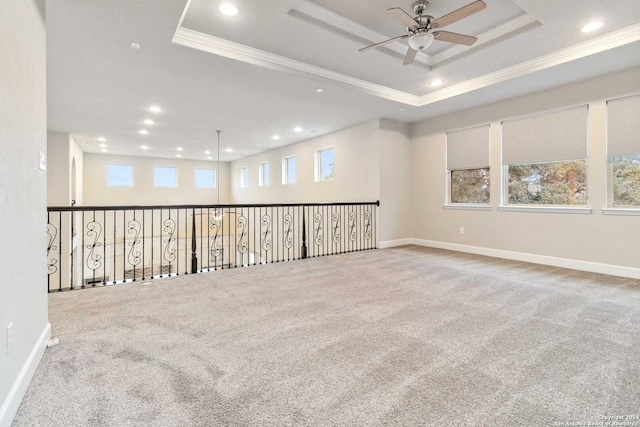 carpeted spare room with a tray ceiling, plenty of natural light, ornamental molding, and ceiling fan