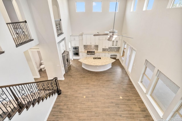 foyer entrance with hardwood / wood-style flooring, ceiling fan, and a high ceiling