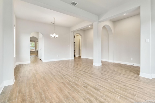 spare room featuring a chandelier and light wood-type flooring