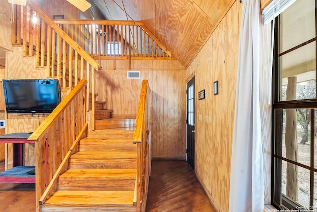 staircase featuring hardwood / wood-style flooring, a towering ceiling, and wooden walls