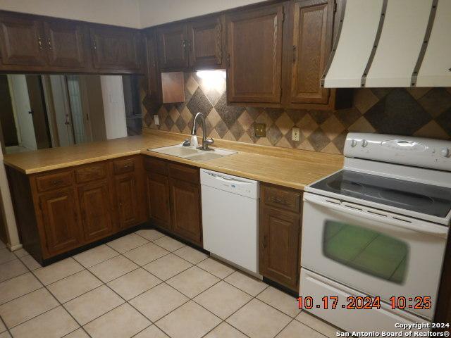 kitchen with decorative backsplash, white appliances, ventilation hood, sink, and light tile patterned flooring