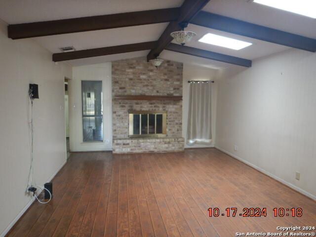 unfurnished living room featuring a fireplace, hardwood / wood-style floors, and vaulted ceiling with beams