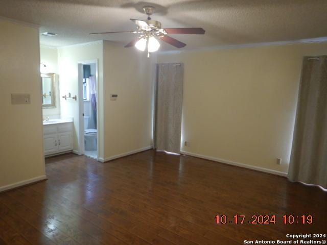 unfurnished bedroom featuring ensuite bath, ceiling fan, crown molding, and dark hardwood / wood-style floors