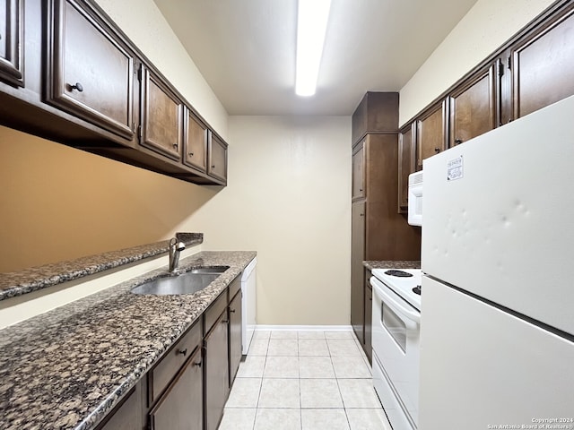 kitchen featuring white appliances, sink, dark stone countertops, light tile patterned floors, and dark brown cabinets