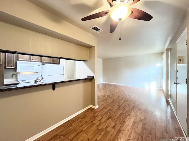 kitchen featuring hardwood / wood-style floors, white appliances, ceiling fan, and dark stone countertops