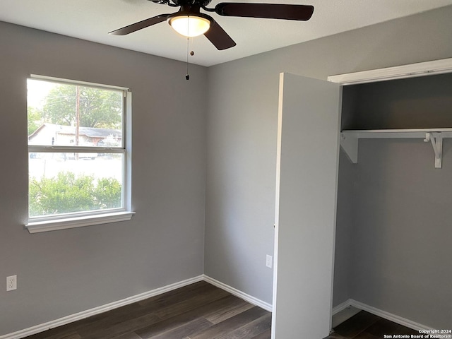 unfurnished bedroom with dark hardwood / wood-style flooring, a closet, and ceiling fan