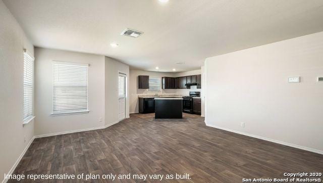 kitchen featuring dark brown cabinetry, dishwasher, a center island, dark hardwood / wood-style floors, and stainless steel range with electric cooktop