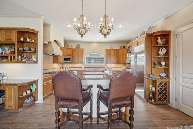 kitchen with built in appliances, light stone countertops, an island with sink, and dark wood-type flooring