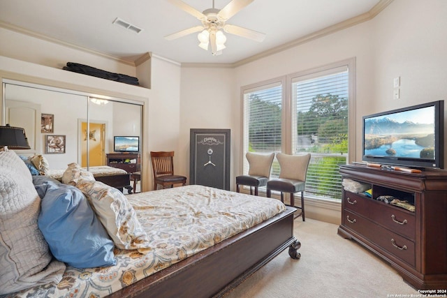 bedroom featuring ceiling fan, a closet, crown molding, and light carpet