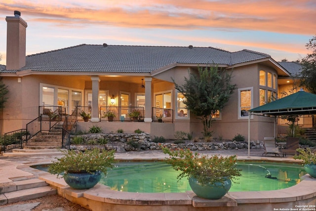 back house at dusk featuring a patio area