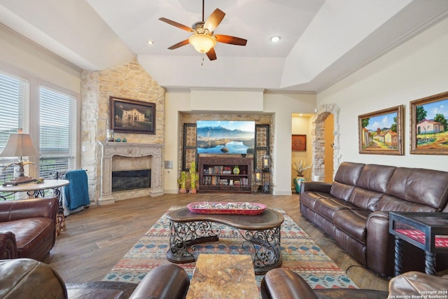 living room featuring a raised ceiling, ceiling fan, hardwood / wood-style flooring, a fireplace, and lofted ceiling