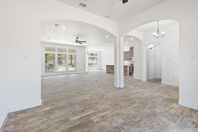 unfurnished living room featuring ceiling fan with notable chandelier and light wood-type flooring