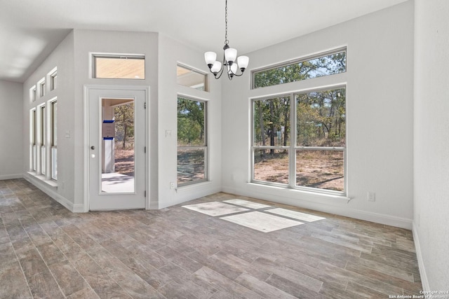 unfurnished dining area featuring a chandelier, a wealth of natural light, and wood-type flooring