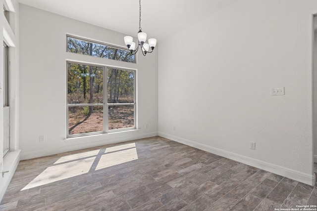 unfurnished dining area with dark wood-type flooring and an inviting chandelier