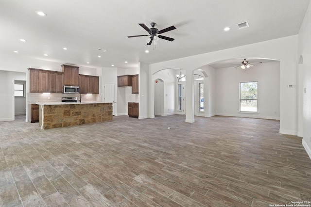 unfurnished living room featuring wood-type flooring and ceiling fan