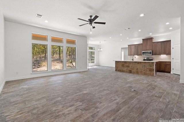 unfurnished living room with wood-type flooring, ceiling fan with notable chandelier, and sink