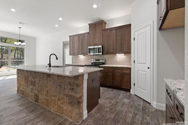 kitchen featuring dark wood-type flooring, a kitchen island with sink, sink, and stainless steel appliances