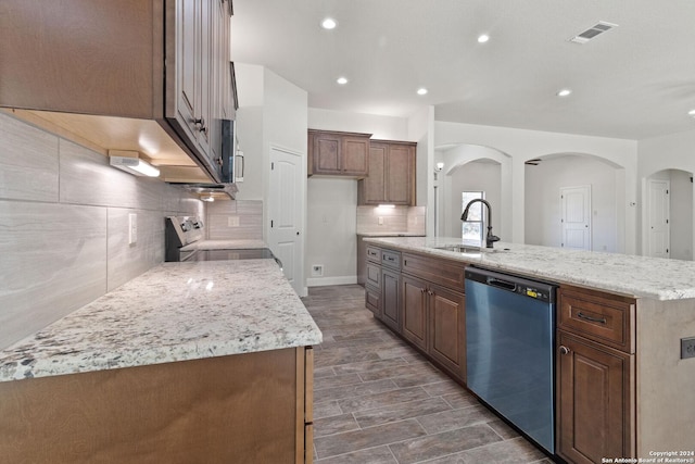 kitchen featuring light stone counters, sink, an island with sink, and appliances with stainless steel finishes