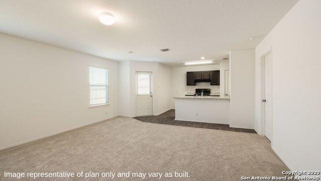 unfurnished living room featuring dark colored carpet