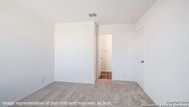 unfurnished bedroom with light colored carpet, a spacious closet, and a closet