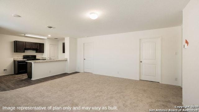 kitchen with dark colored carpet, dark brown cabinets, and kitchen peninsula