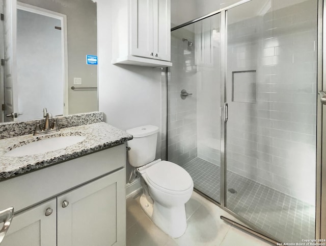 bathroom featuring toilet, vanity, tile patterned floors, and a shower with shower door