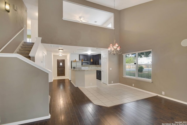 unfurnished living room with high vaulted ceiling, wood-type flooring, and a notable chandelier