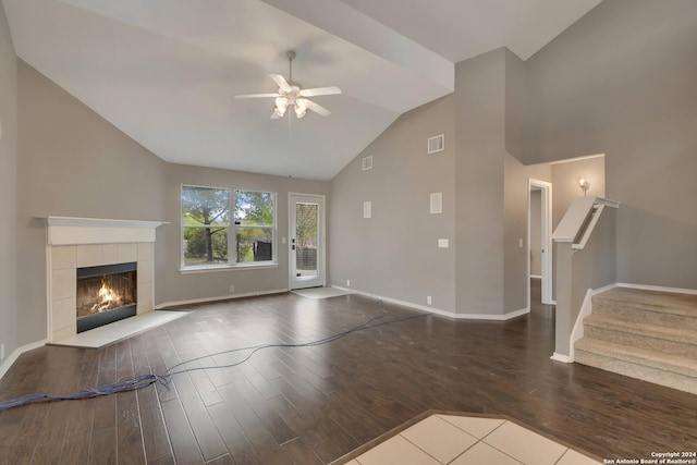 unfurnished living room with a tiled fireplace, ceiling fan, wood-type flooring, and lofted ceiling