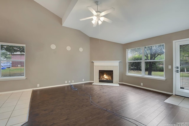 unfurnished living room featuring a tile fireplace, ceiling fan, wood-type flooring, and lofted ceiling