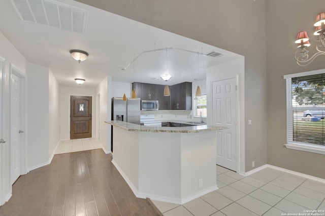 kitchen with light hardwood / wood-style floors, light stone countertops, and stainless steel appliances